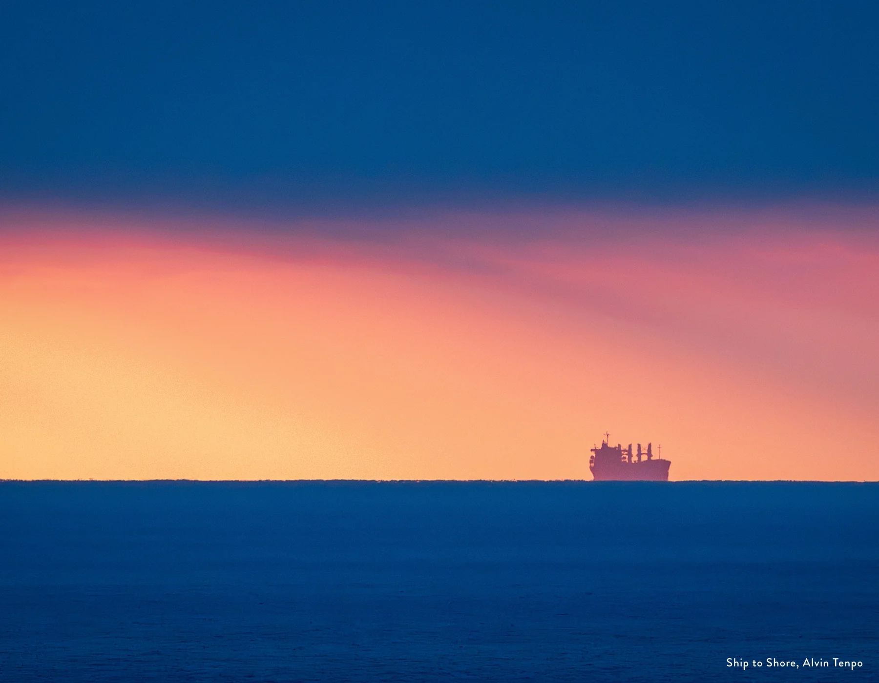 A ship on the ocean horizon under an orange and pink sky, photo by Alvin Tenpo for the 2027 People's Calendar